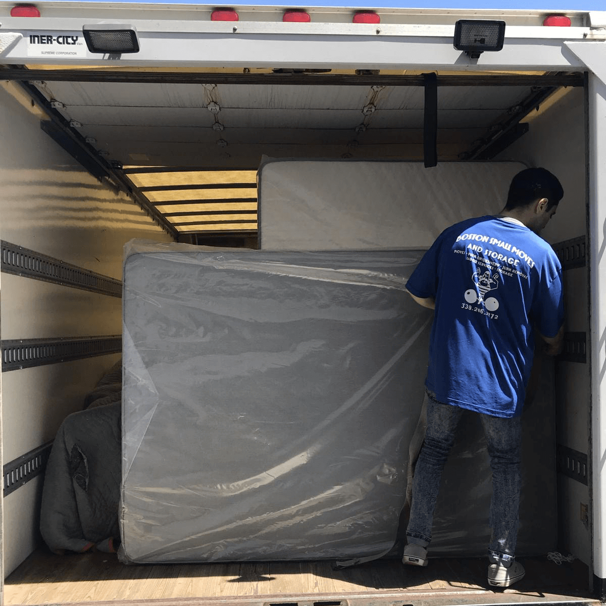 Boston Small Moves team member loading a protected mattress into the moving truck