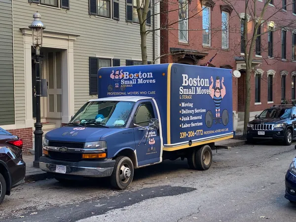 Blue Boston Small Moves truck parked beside neighborhood homes