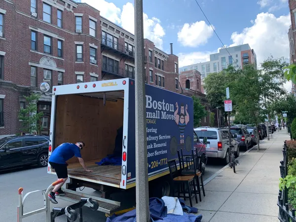 Crew loading a moving truck with furniture and moving blankets nearby