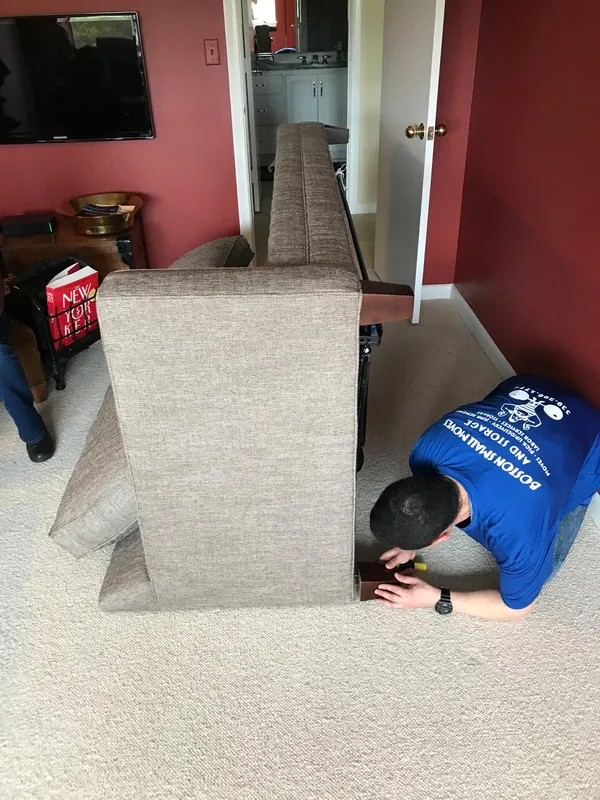 Mover removing a sofa leg to prepare it for moving